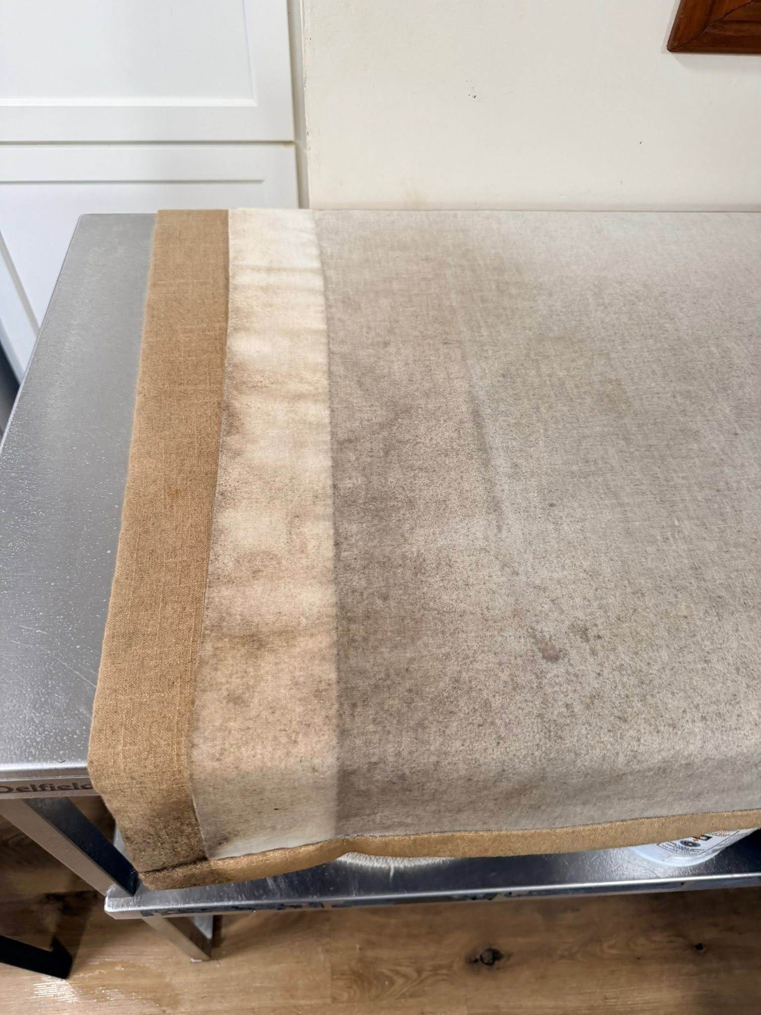 A lined drapery panel before cleaning, with a gray film across the face fabric